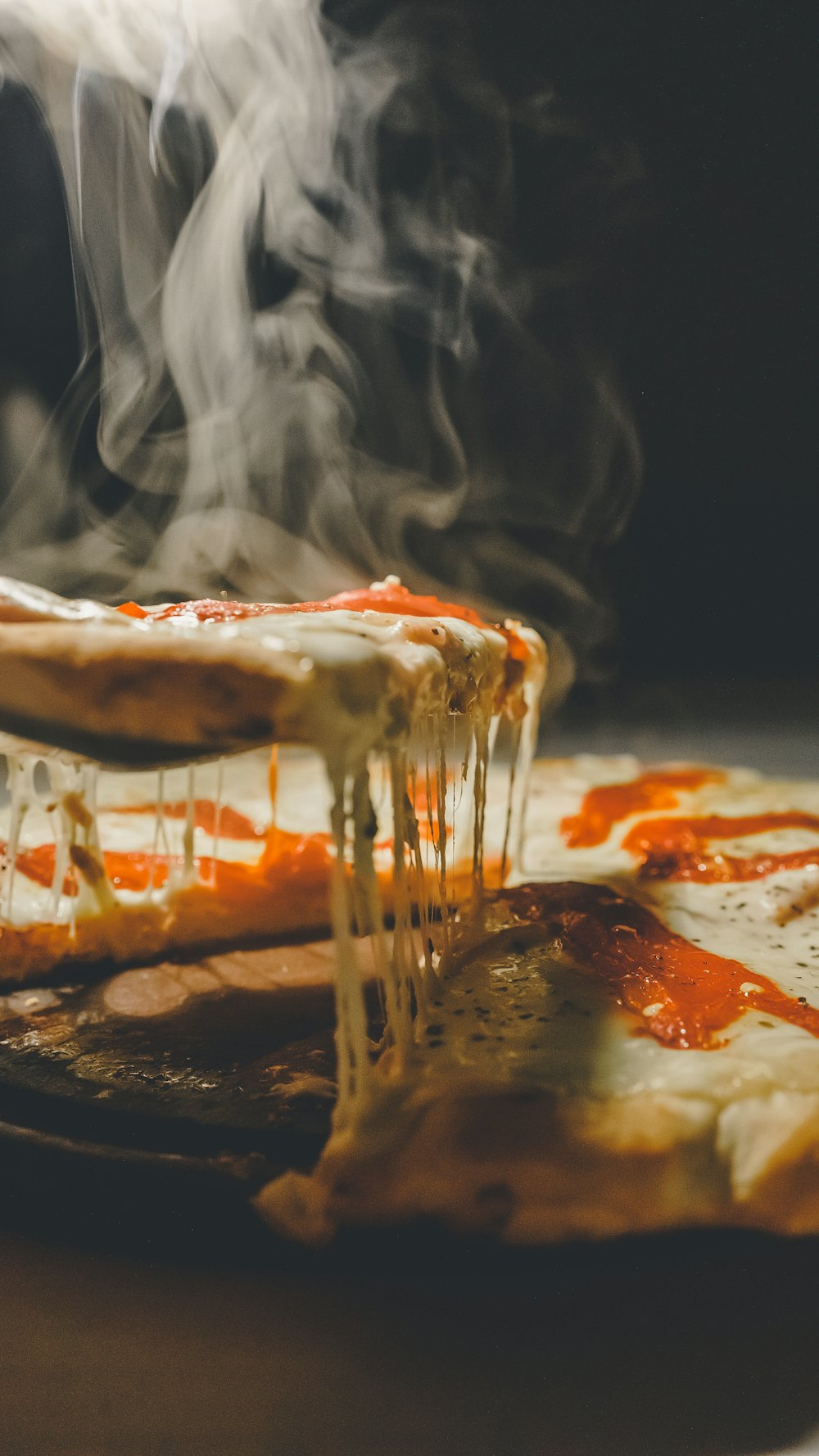 Fatia de pizza com queijo a esticar e vapor, fotografada em movimento