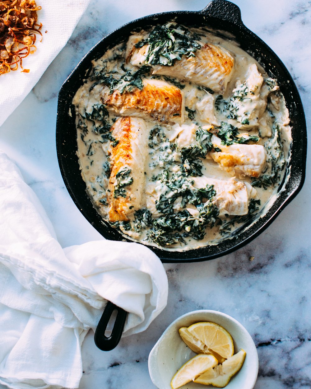 Peixe cozinhado em panela com molho e espinafres
