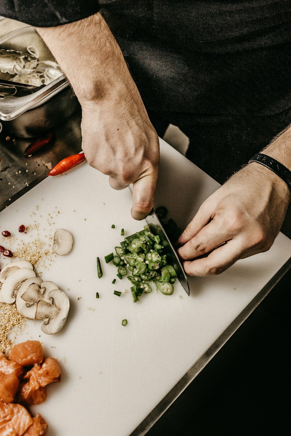 Mãos a preparar e cortar ingredientes numa tábua na cozinha da taberna